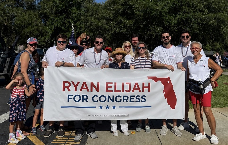 Ryan Elijah volunteers holding a Ryan Elijah for Congress banner at a Central Florida parade